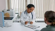 Picture of a patient and doctor sat at a desk having a conversation